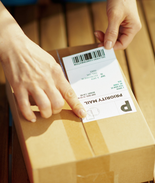 Eine Person befestigt ein Etikett auf einem Paket.